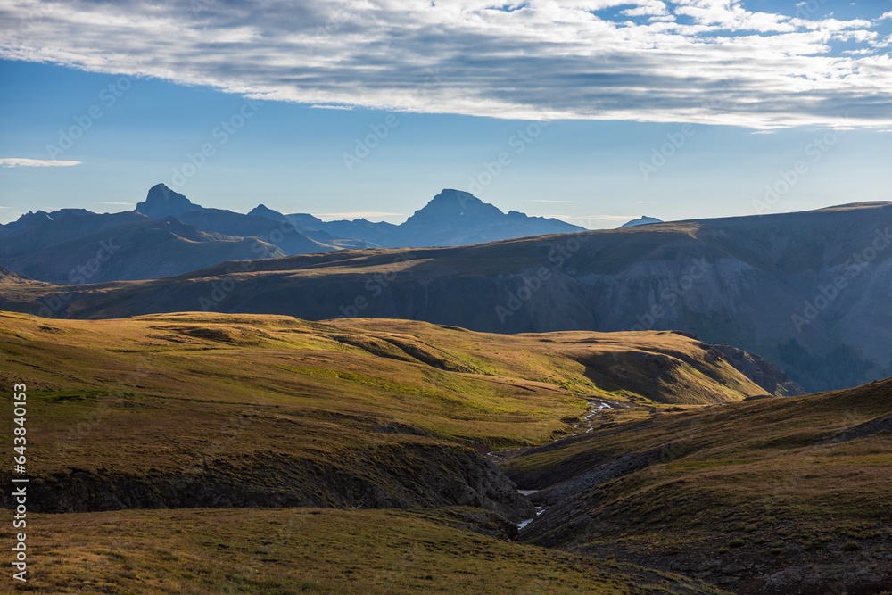 Mountain sunrise over tundra meadow stream with distant peaks
