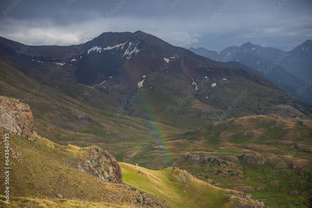 Mountain storm with pools of light and rainbow