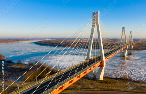 Aerial view of multispan cable-stayed Murom Bridge across ice covered Oka river on sunny winter day, Vladimir region, Russia. © JackF