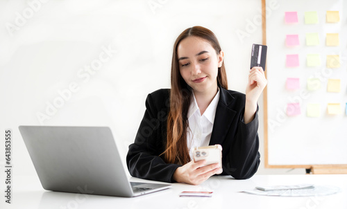 Asian girl shopping online holding credit and using smartphone enter their card number in the mobile phone app to purchase and payment in Internet store