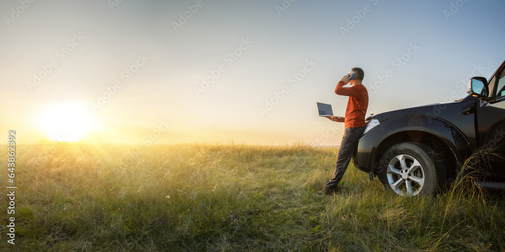 businessman doing remote business near his car at the meadow with computer. bannert with copy space. businessman doing remote business near his car at the meadow with computer. bannert with copy space.