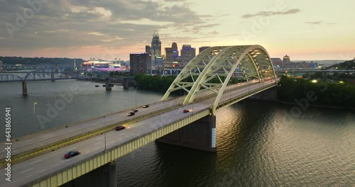 Highway traffic on Daniel Carter Beard Bridge in Cincinnati, Ohio with brightly illuminated high skyscraper buildings in downtown district. American city with business financial district at sunset photo