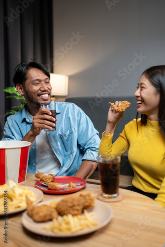 Group of Asian male and female friends having fun and celebrating a fast food feast with soft drinks on the table during a happy friends gathering party and smiling  cheerful  delicious weekend.