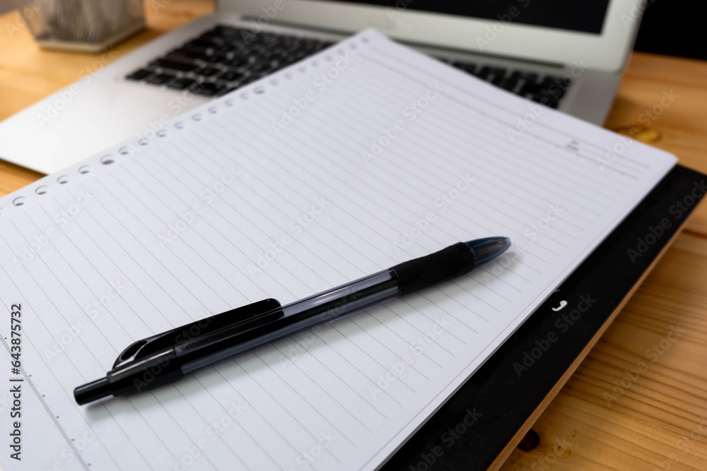 Image of workplace in office room without people with open laptop, pencil and notebook lying on wooden desk Image of workplace in office room without people with open laptop, pencil and notebook lying on wooden desk
