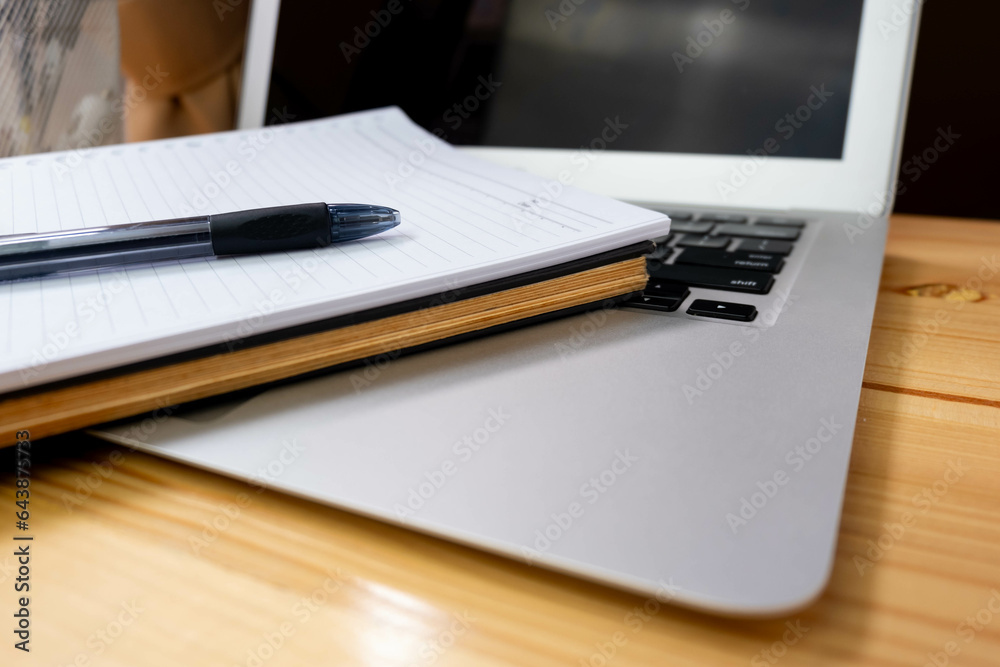 Image of workplace in office room without people with open laptop, pencil and notebook lying on wooden desk Image of workplace in office room without people with open laptop, pencil and notebook lying on wooden desk