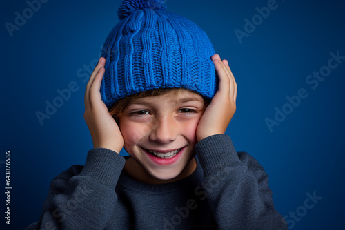 a boy with a blue knitted hat is laughing on background
