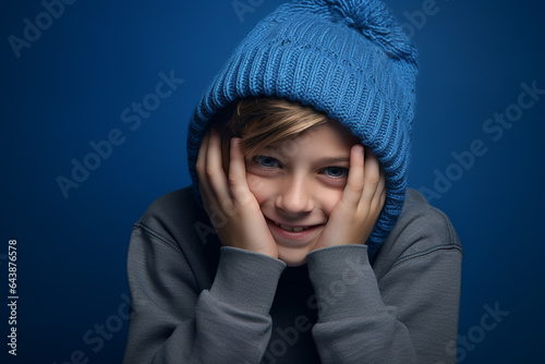 a boy with a blue knitted hat is laughing on background