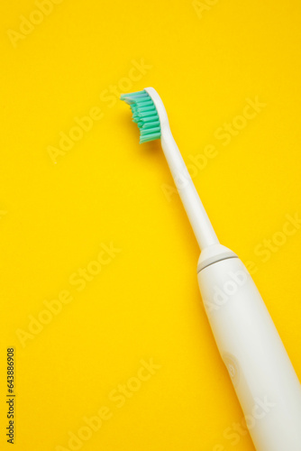 Smart electric toothbrush on yellow background. Healthy teeth. Dentistry. Medical robot. Vertical photo