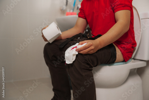 Man using tissue paper in the toilet for relief, health and wellness, hemorrhoids and personal hygiene