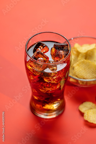 Refreshing glass of cola with ice, accompanied by a serving of crispy chips