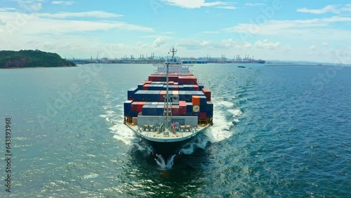 Aerial front view of a container ship sailing at the sea for transportation.