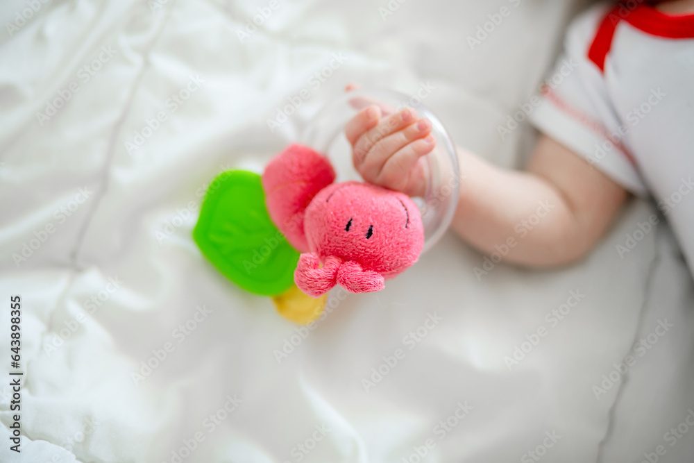 The rattle in the hands of a newborn baby. The first attempts to hold a toy in a baby The rattle in the hands of a newborn baby. The first attempts to hold a toy in a baby