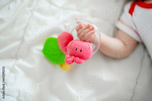 The rattle in the hands of a newborn baby. The first attempts to hold a toy in a baby
