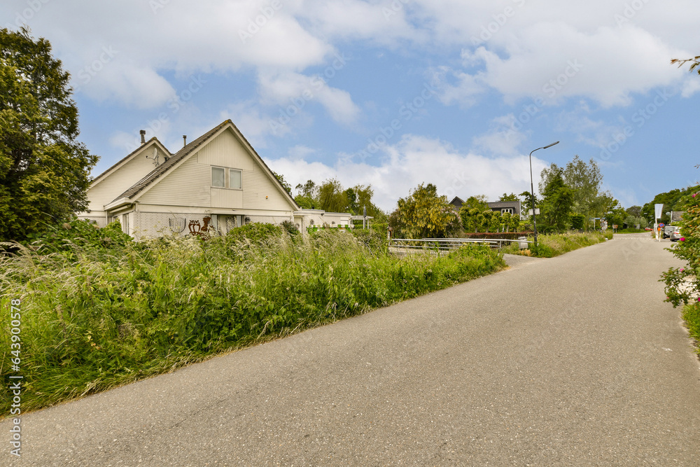 a house on the side of a road with weeds growing in front and bushes along the path leading up to it a house on the side of a road with weeds growing in front and bushes along the path leading up to it