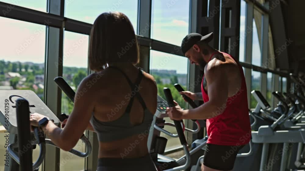 After an intense gym session, a sporty young man and woman in workout attire express their approval with a celebratory handclasp