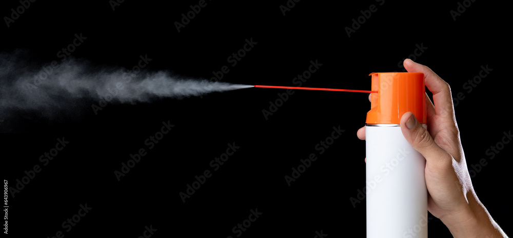 Hand holding a unlabeled white aerosol can with spray in black back ...