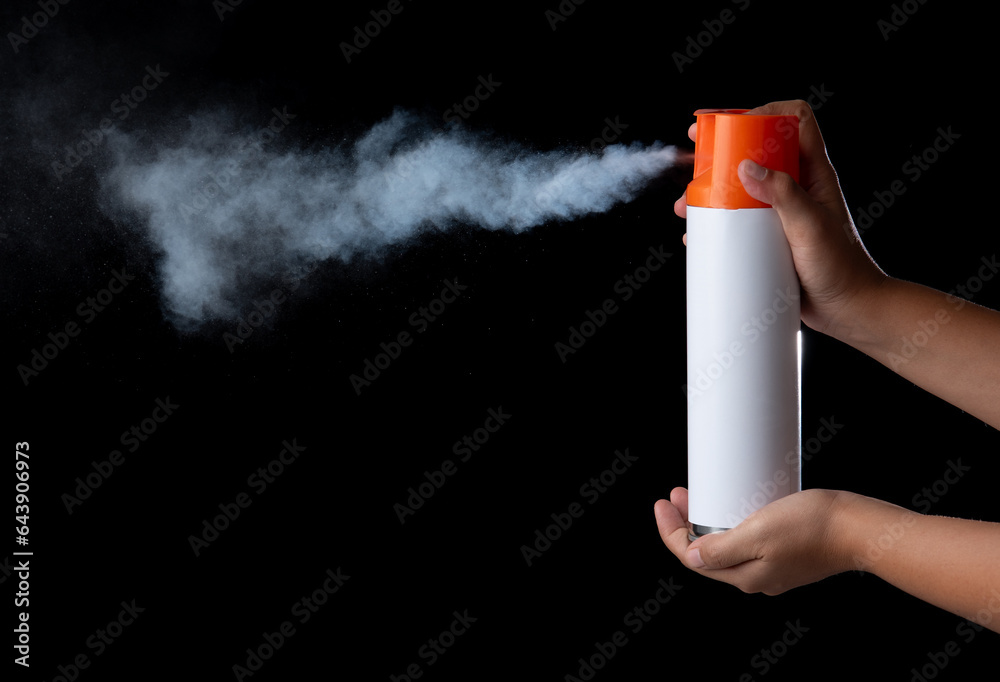 Hand holding a unlabeled white aerosol can with spray in black back ...