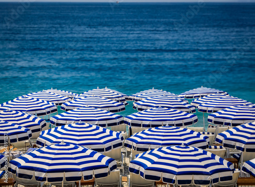 Pebble beach along Promenade des Anglais with beach umbrellas and chairs with th фототапет