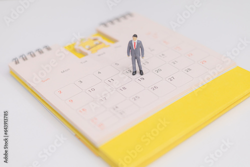Miniature people businessman stands on yellow calendar. business and financial concept. Event planner schedule agenda plan on schedule event. Calendar event schedule, work planning.
