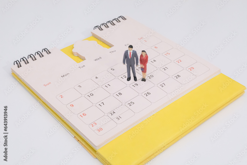 Miniature couple people businessman standing on yellow calendar. business and financial concept. Event planner schedule agenda plan on schedule event. Calendar event schedule, work planning. Miniature couple people businessman standing on yellow calendar. business and financial concept. Event planner schedule agenda plan on schedule event. Calendar event schedule, work planning.