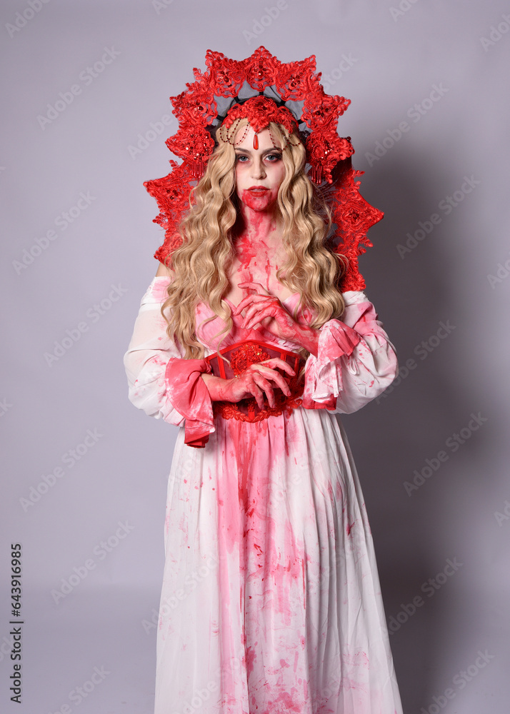 Close up portrait of scary vampire zombie queen, wearing elegant halloween fantasy costume with crown and bloody red paint splatter. Isolated on studio background with gestural hands reaching out tow Close up portrait of scary vampire zombie queen, wearing elegant halloween fantasy costume with crown and bloody red paint splatter. Isolated on studio background with gestural hands reaching out tow