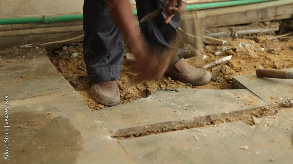 Hard working labour removing old tiles using hammer. Breaking tiles