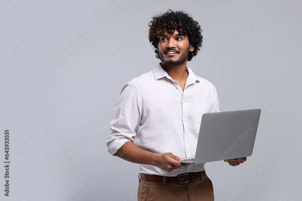 Smiling man with laptop on light grey background, space for text Smiling man with laptop on light grey background, space for text