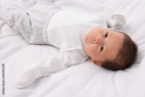 Cute newborn baby lying on white soft bed