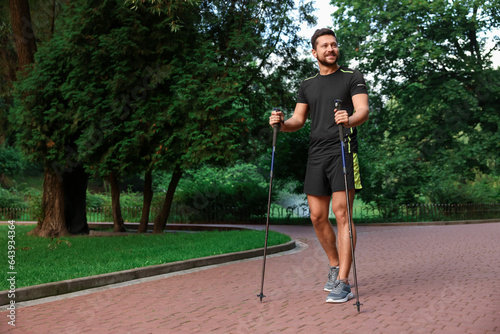 Man practicing Nordic walking with poles outdoors. Space for text
