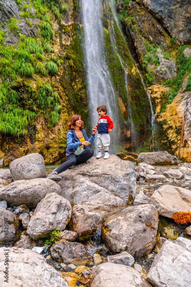 Obraz premium Mother with her son Grunas waterfall in Theth national park, Albania. Albanian alps