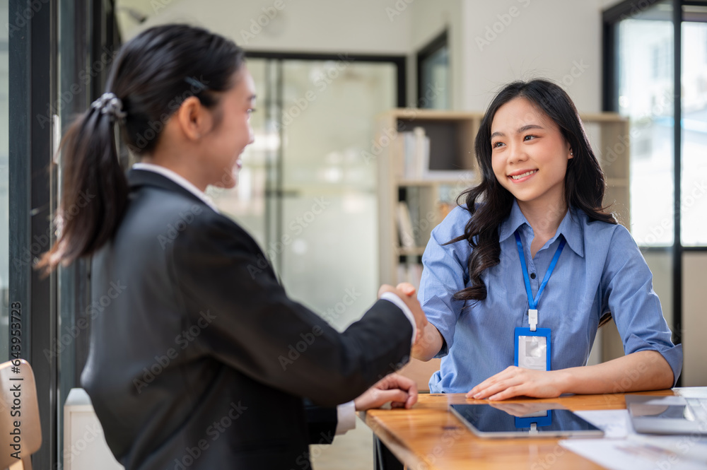 Two happy Asian businesswomen are shaking hands after a meeting in the office. Two happy Asian businesswomen are shaking hands after a meeting in the office.
