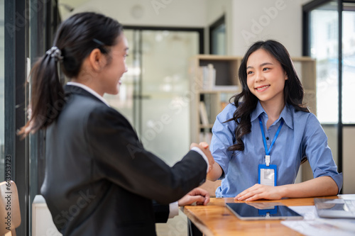 Two happy Asian businesswomen are shaking hands after a meeting in the office.