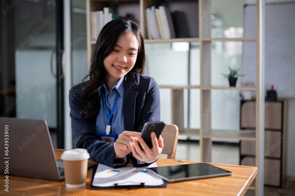 A beautiful Asian businesswoman is checking SMS or sending messages to someone on her smartphone. A beautiful Asian businesswoman is checking SMS or sending messages to someone on her smartphone.
