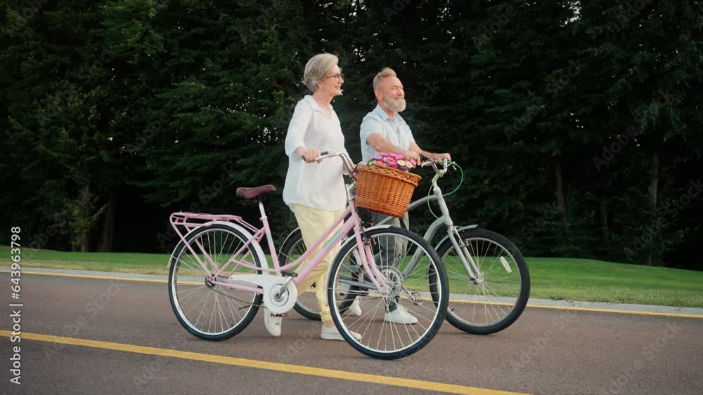 Senior family of two having promenade with bicycles outdoors Senior family of two having promenade with bicycles outdoors