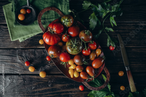 Still life, different varieties of tomato scattered on a wooden table, soft morning light, top view photo