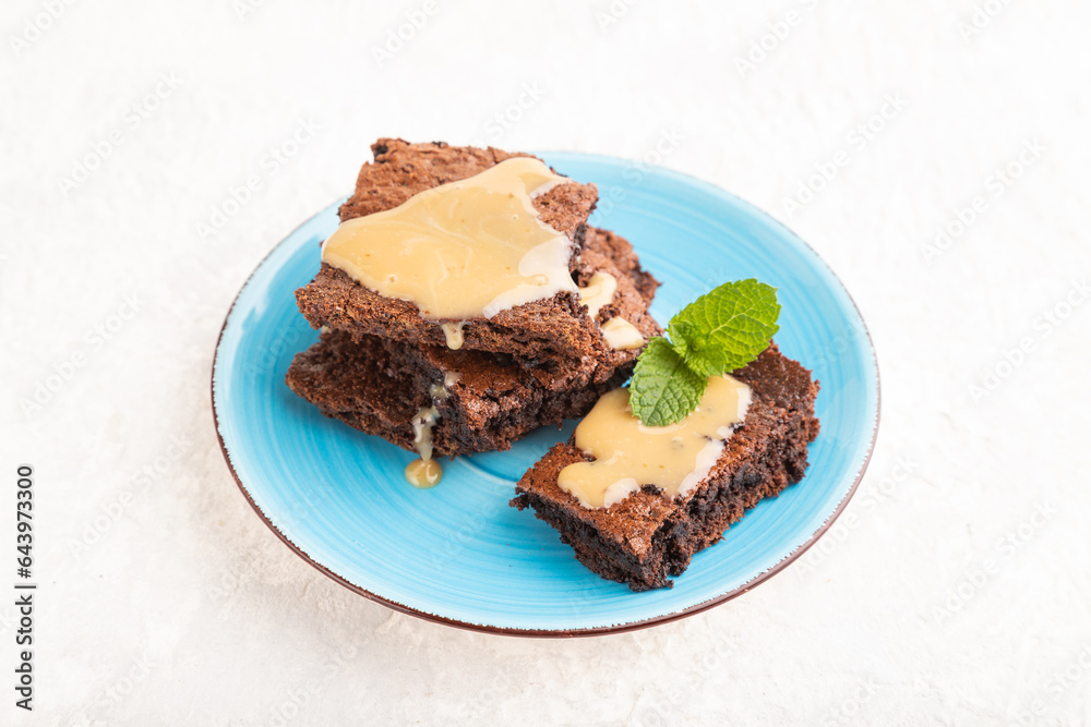 Chocolate brownie with caramel sauce on gray concrete, side view. Chocolate brownie with caramel sauce on gray concrete, side view.