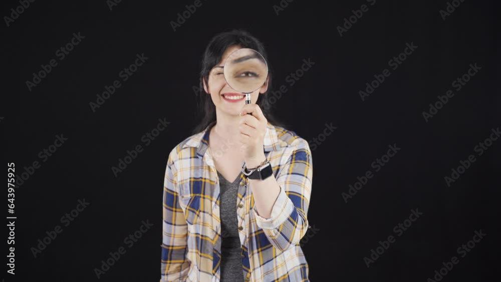 Woman looking at camera with magnifying glass. Woman looking at camera with magnifying glass.