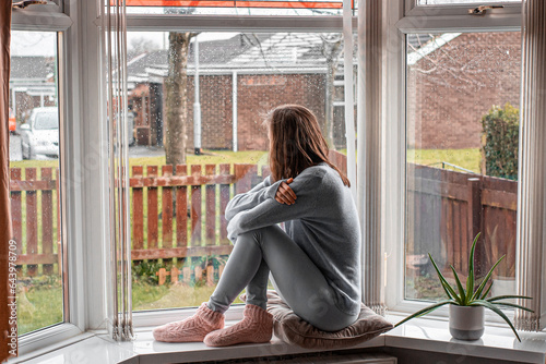 Thoughtful sad woman sitting on a windowsill