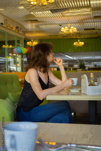 Beautiful woman drinking coffee in cafe. Daily life concept. Enjoy your life concept. Brunette girl with cup of tea on the sofa. Cozy lifesyle. Pretty woman in cafe interior. Coffee break time.