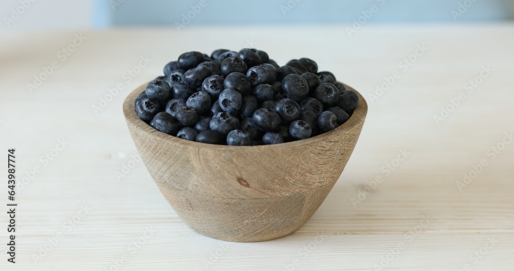 Blueberries in a wooden bowl on a white table. Ripe berries Close-up. Blueberries in a wooden bowl on a white table. Ripe berries Close-up.