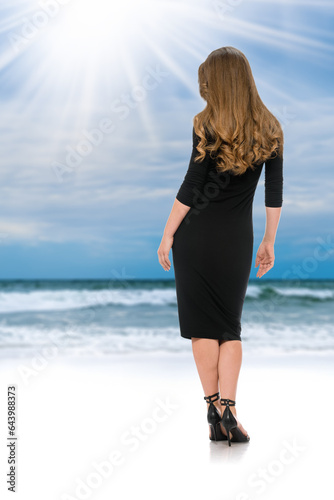 Fotografie Back view of stunning blonde with wavy hair in long black dress and black heels