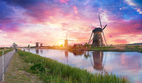 Landscape with tulips, traditional dutch windmills and houses near the canal in Zaanse Schans, Netherlands, Europe. High quality photo #643988756
