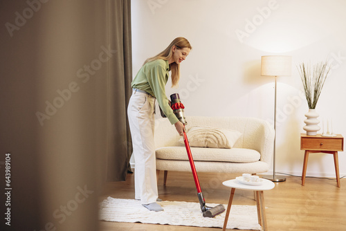 Woman doing house work and using wireless vacuum cleaner