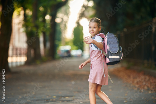 Hello hand gesture. Schoolgirl with backpack is outdoors