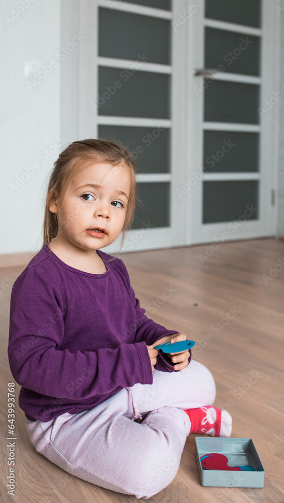 Little girl plays an educational game at home. Preschooler learns shapes indoors. Homeschooling concept. Little girl plays an educational game at home. Preschooler learns shapes indoors. Homeschooling concept.