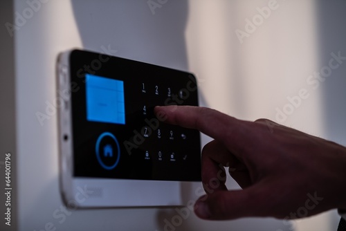 Man enters the code into the alarm using the alarm system's keypad on the wall in the home