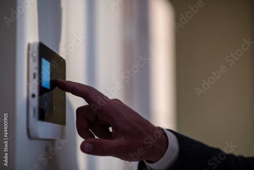 Man enters the code into the alarm using the alarm system's keypad on the wall in the home