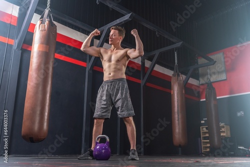 Handsome and muscular white man lifts heavy dumbbells, showcasing his impressive physique and strength in the gym © asean studio