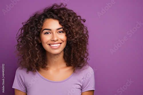Smiling confident young woman with dark curly hair on a purple background