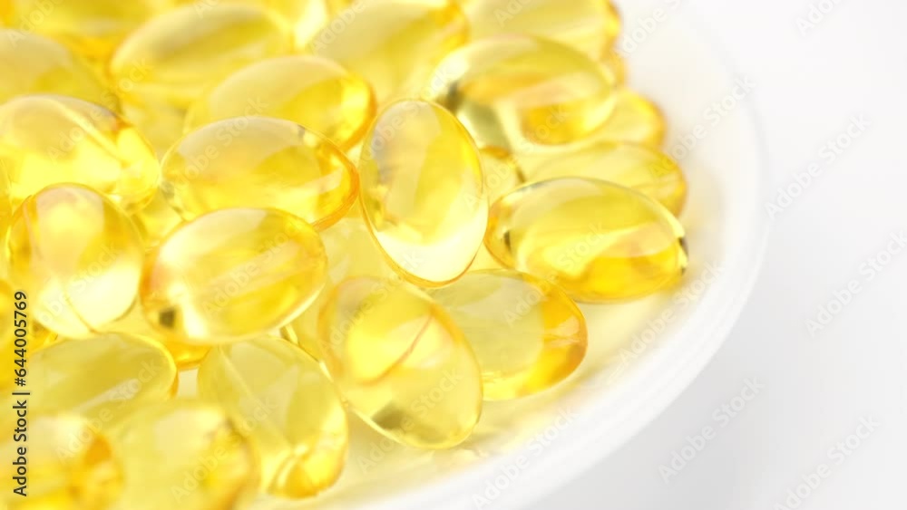 Yellow softgel capsule Vitamins Omega 3 or fish oil in white plate, rotate. Pharmaceutical industry Yellow softgel capsule Vitamins Omega 3 or fish oil in white plate, rotate. Pharmaceutical industry